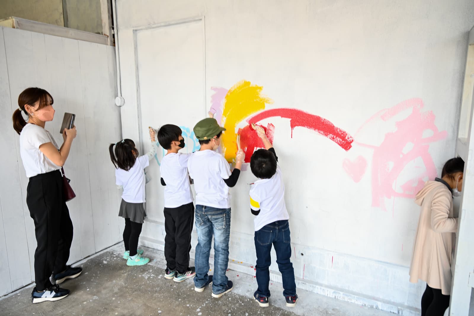 ウォールアートで大きな壁に絵を描く子どもたち